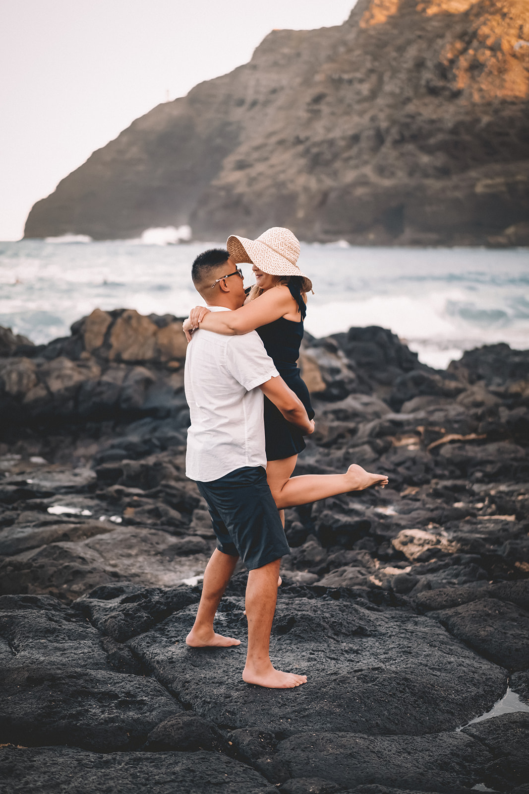 man holding woman with sun hat makapuu beach