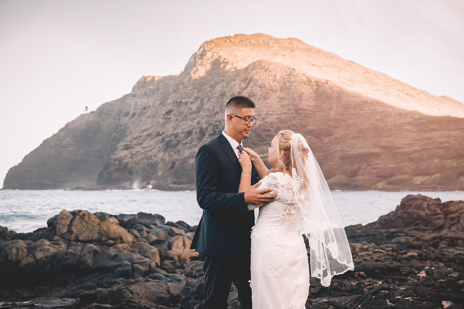 bride adjusting groom's tie on makapuu beach