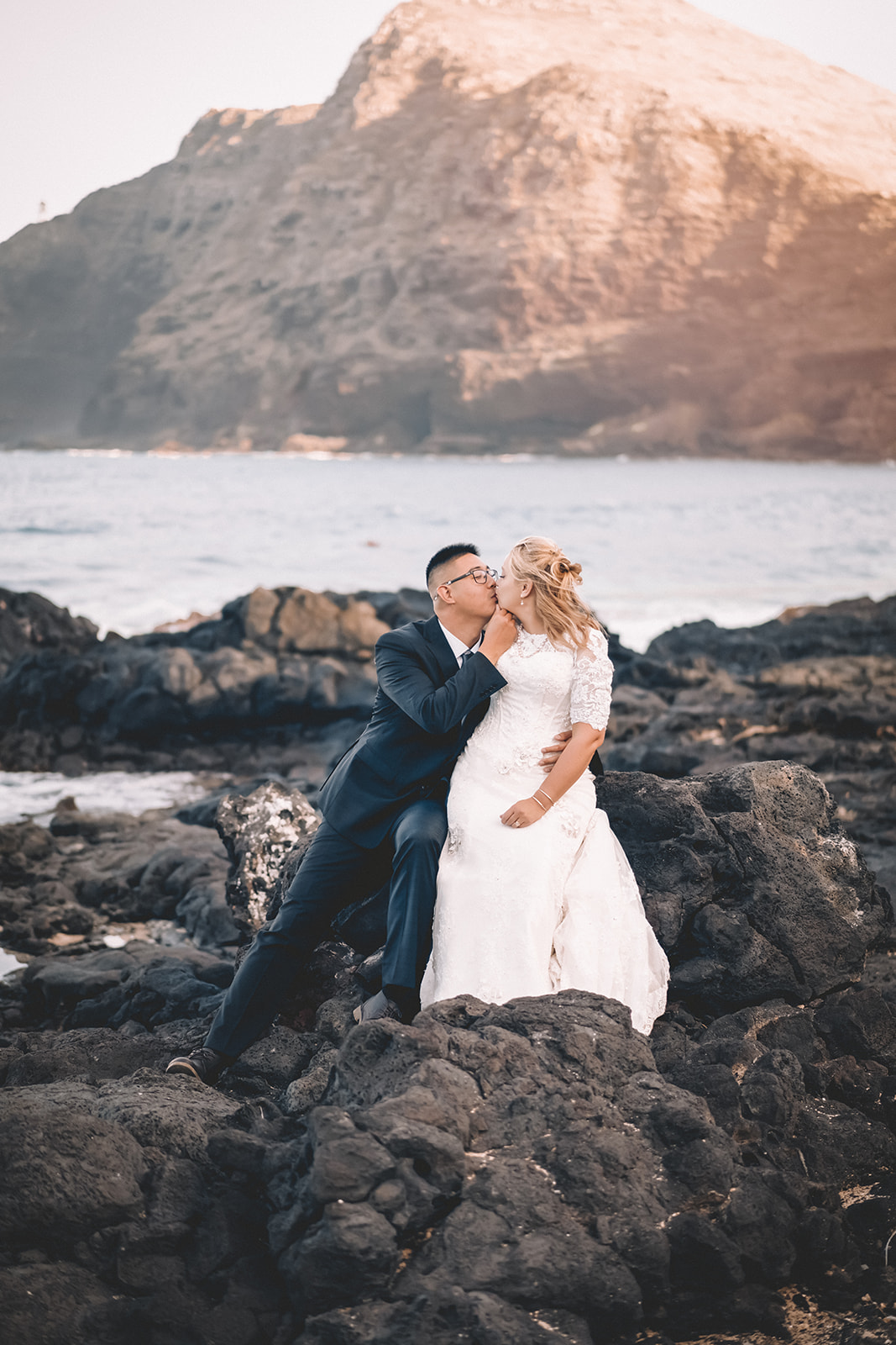 engaged couple Hawaii kissing on rock wall Makapuu beach