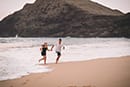 man and woman running out of ocean makapuu beach