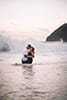 man and woman embracing in shallow water wave crashing