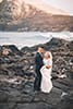 bride and groom holding eachother in middle of rock wall makapuu beach