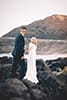 bride and groom holding hands rock wall makapuu beach Hawaii
